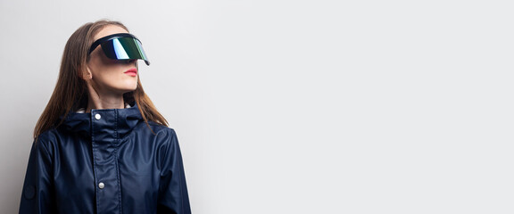 Young woman in virtual reality glasses looks to the side on a light background. Banner