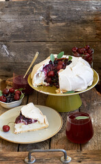 Pavlova cake with blueberry curd, cherries, blueberries and sage. Side view. Wooden background.