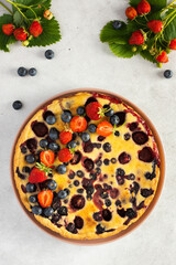 Strawberry blueberry pie decorated with fresh berries on a gray background, top view