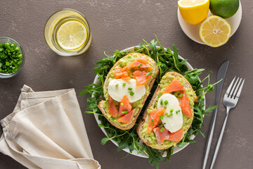 Delicious hearty breakfast, sandwiches with avocado paste, salmon and mozzarella on a plate with arugula and pea sprouts