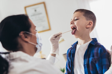 Doctor checking little boy's throat in the office