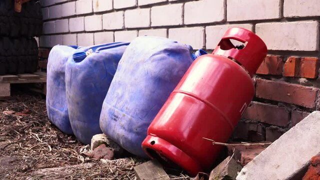 a red propane canister stands against the wall next to the canisters