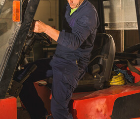 Unrecognizable young man getting off a forklift.