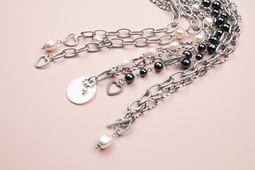 Close up of chain necklaces with white baroque pearl pendant on pastel pink background