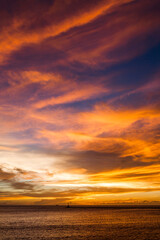 Fototapeta na wymiar Brilliant orange-red clouds reflected into the ocean in a beautiful sunset