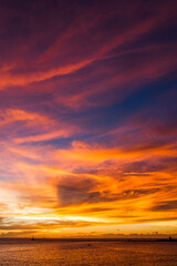 Brilliant orange-red clouds reflected into the ocean in a beautiful sunset
