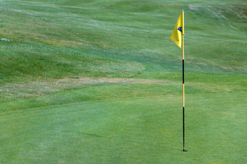 Obraz premium A yellow flag on a pole in a hole on a golf course