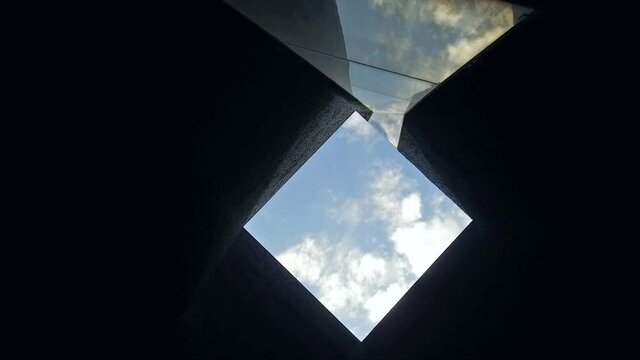 Low Angle Shot Of Camera Rotating In Square Ceiling Architecture Detail. Blue Sky Background.