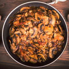 Vegetarian stew with mushrooms in a plate, close-up, top view on the table.