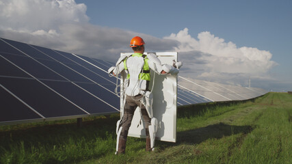 Man in exoskeleton taking solar panel from colleague