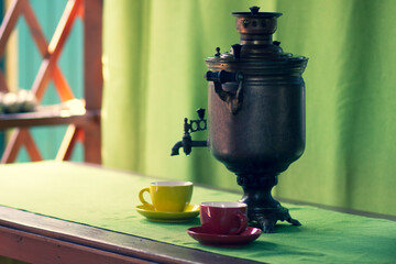 Russian copper samovar and tea cups on the table in the gazebo