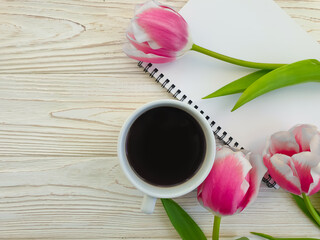 coffee cup, paper notebook, tulip on wooden background