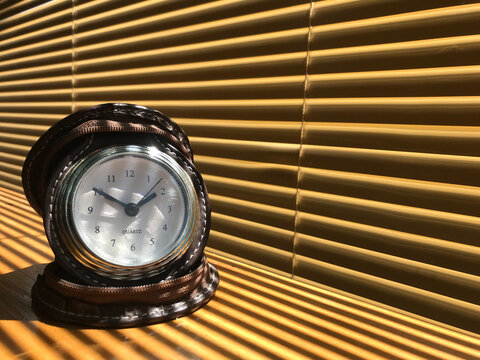 The clock is on a brown wooden table.