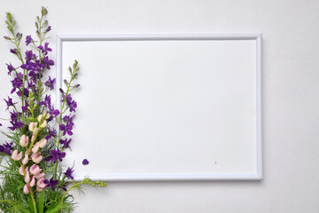 A white frame and a bouquet of purple flowers. Mockup