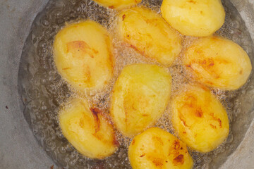 Golden potatoes are fried in boiling oil in a cauldron