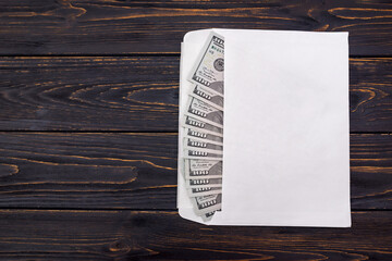 dollars in a white envelope on a wooden background