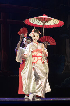 Japanese women in traditional kimono dansing with umbrella and fans. Traditional Japanese performance.