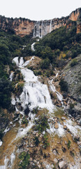 A large waterfall over a rocky hill