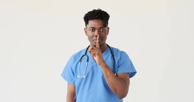 Male doctor in blue uniform and stethoscope gesturing stop sign with hand over white background