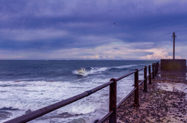Obraz premium Fishing motor boat coming into shore at Port Alfred on a cold stormy late afternoon
