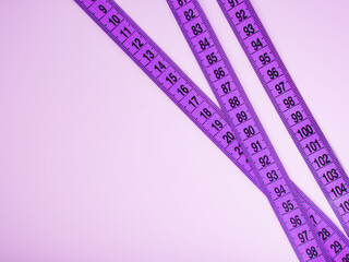 Bright purple tape measure on violet background with copyspace