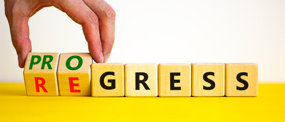 Regress or progress symbol. Businessman turns wooden cubes and changes the word 'regress' to...