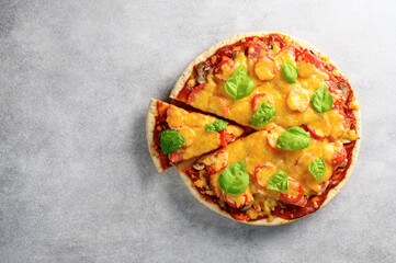Top view of hot tasty homemade pizza with green basil leaves on the grey concrete background. With copy space for text. Flat lay
