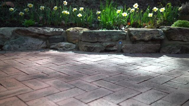 Slider to the left with brick herringbone pavers in focus, rock wall background