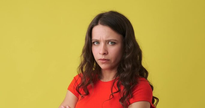 Stubborn woman showing her displeasure and making funny faces over yellow background