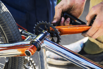 Bicycle repair. The process of installing the pedal and tensioning the chain. Close-up. Unrecognizable person.