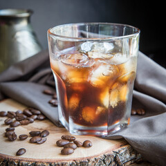 An iced coffee, a cezve and a milk jug on a wooden table and black background .  Refreshning . 