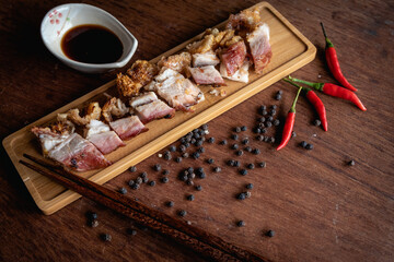 Closed up dipped of crispy pork with original sauce by chopstick for ready to eat on wooden background