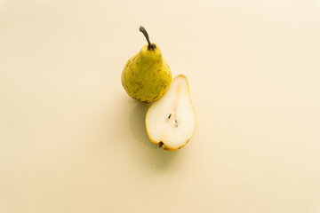 Fototapeta na wymiar Fresh pear and sliced juicy pear on beige background. Creative concept.
