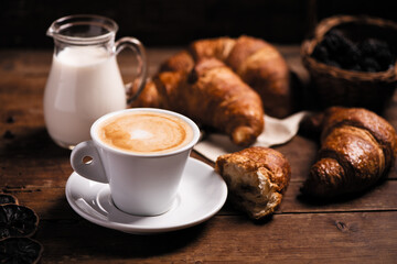 Coffee cup with a croissant on a rustic wooden table