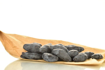 Lots of dark purple organic honeysuckle berries on a craft paper bag, close-up, isolated on white.