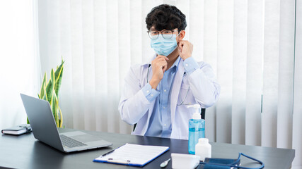 Fototapeta premium Medical concept a male doctor wearing mask and using hand sanitizer alcohol gel for preventing against infection of Coronavirus (Covid-19) outbreak at his modern clinic