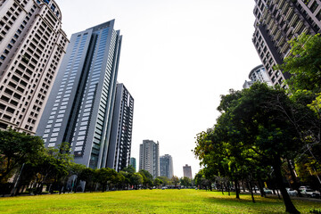 Low angle view of park green space and modern buildings on both sides in downtown Taichung, Taiwan....