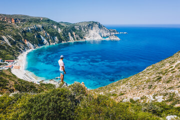 Man standing on top of a rock with an exciting feeling of freedom, looking at Myrtos Beach....
