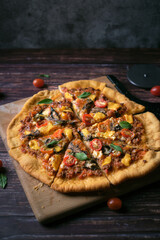 Fresh baked thin crust Italian pizza with tomato sauce pepper cheese and basil leaf on Dark rustic table background.