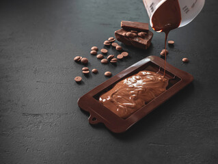 Homemade natural chocolate on a black background. Manufacturing process.