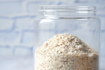 Fototapeta na wymiar Close up of oats flakes in a glass jar on table 