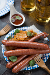 Blue and white carton plate with smoked sausages, stewed cabbage and beer, vertical shot, selective focus