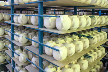 billets of ceramic white teapots in rows on the shelves in the production shop at the porcelain factory in the Moscow region