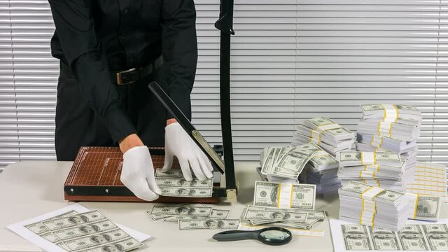 Сounterfeiter cuts money in a clandestine laboratory.