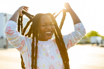 Happy young woman with dreadlocks outdoors
