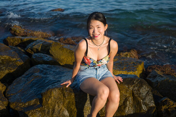 Fototapeta na wymiar young happy and beautiful Asian woman by the sea - Attractive Korean girl cheerful enjoying relaxed summer holidays at tropical island in travel and lifestyle concept