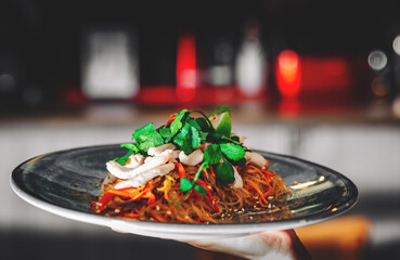 Waiters hand holding a plate with food in cafe or restaurant