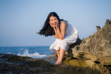 Fototapeta na wymiar young happy and beautiful Asian woman by the sea - Attractive Korean girl in white dress enjoying relaxed summer holidays at tropical island in travel and lifestyle concept