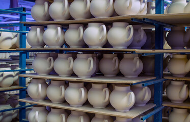billets of ceramic white teapots in rows on the shelves in the production shop at the porcelain factory in the Moscow region - obrazy, fototapety, plakaty