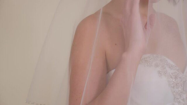 Close-up portrait of a bride in a dress with a veil that covers her head.